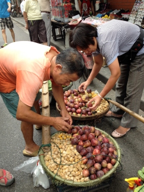 Street fruit vendor - he carries the fruit baskets from a long bamboo yoke.